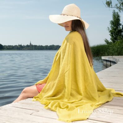Żółty ręcznik plażowy wytkany w paski.
